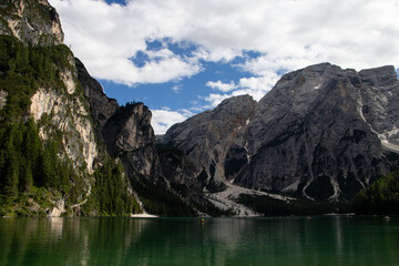 Fototapeta premium Photography of Lago di Braies, Italy, showing the turquoise alpine lake surrounded by mountains, pine forests, and scenic natural landscape in the Dolomites.