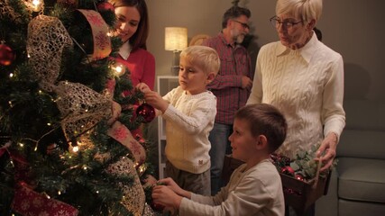 Family decorating christmas tree together at home