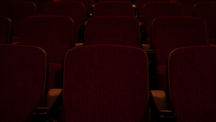 Rows of empty, plush red theater seats, awaiting an audience.