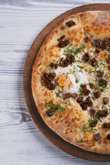 Homemade pizza with meat chunks and egg. Freshly baked meat and egg pizza close up. Gourmet egg and meat topped pizza.