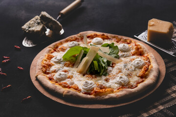 Delicious four cheese pizza on dark background. Homemade Italian four cheese pizza. Freshly baked quattro formaggi pizza. Traditional Italian pizza with four cheeses.
