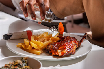 grilled chicken and french fries, salting the potatoes chips, african american eating fast food