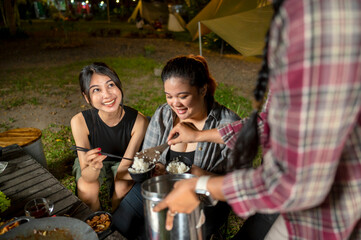 Indonesian southeast asian woman served cooked rice to others while camping. The scene of the lifestyle of enjoying food in a natural setting
