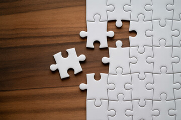 Obraz premium Solving white jigsaw puzzle on wood table for business strategy and problem solving concept idea design