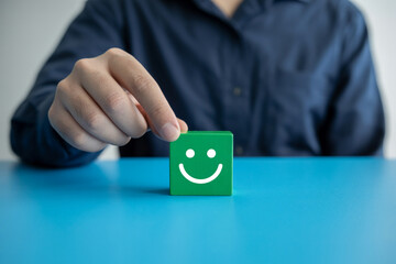 Customer feedback satisfaction rating concept with green cube and smiling face icon on blue table top