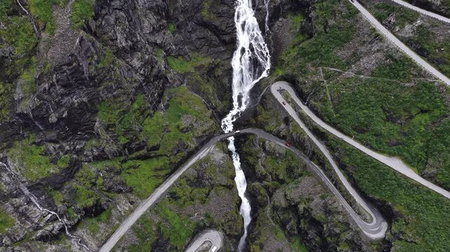 Aerial view of Trollstigen mountain road winding through dramatic hairpin bends and Stigfossen falls