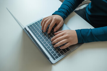 Typing on laptop keyboard for remote work or online learning from home office desk top view concept