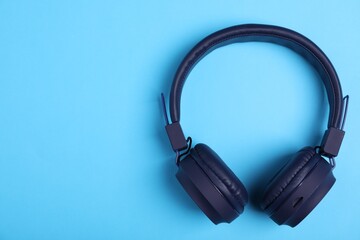 Pair of stylish headphones on light blue background, top view. Space for text