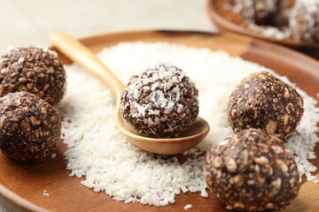 Making tasty chocolate candies with nuts and coconut flakes at light table, closeup