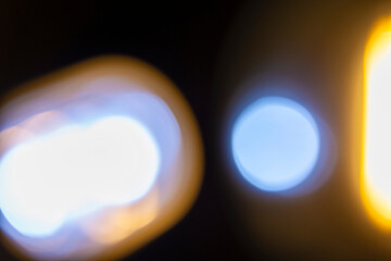 Abstract image showing blurred golden light with bokeh spheres against a dark background, creating a dreamy and atmospheric effect. Decorative element suitable for use as a background
