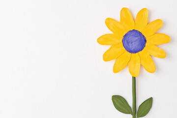 Obraz premium Bright yellow flower with a bold blue center stands against a white background, capturing cheerful simplicity and the charm of handmade botanical art and sunny mood.