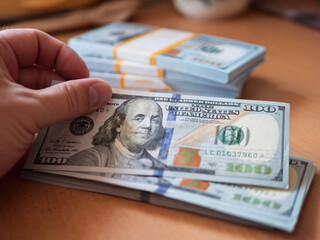 Stacks of Cash: Hand Holding One Hundred Dollar Bills