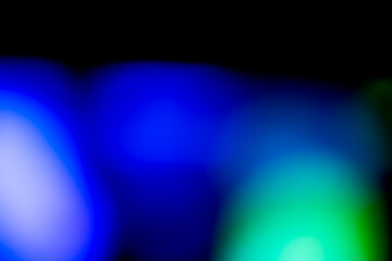 A colorful abstract background featuring blurred light bokeh circles against a dark or black background. The bokeh lights are in colorful, vibrant shades, creating a festive and magical atmosphere