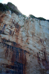 Sun is coming out below a massive cliff with sun rays 