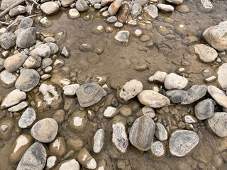 Naturally arranged stones and pebbles in shallow water forming a circular pattern on the riverbed