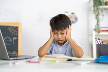 Asian boy stressed homework studying with hands on head, tired expression shows school pressure from parents, education overload with books, online learning, academic pressure and homework frustration