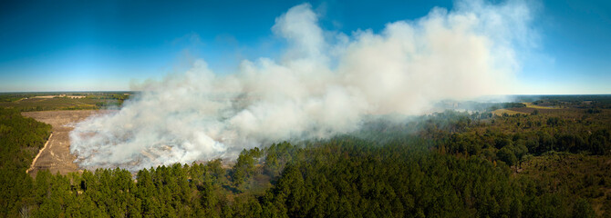 View from above of dense smoke from woodland and field on fire rising up polluting air. Concept of natural disaster