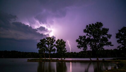 Naklejka premium Night scene of a lake with silhouetted trees and a dramatic lightning strike