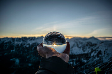 a crystal ball with reflecting sunlight surrounded by winter mountains