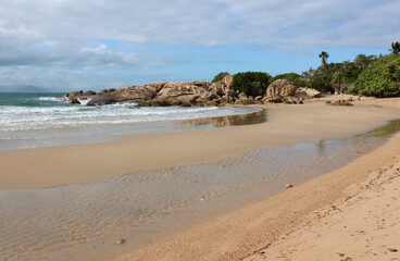Relaxing tropical beach with sand, the ocean, rocks and trees at Rose Bay near Bowen in Queensland, Australia