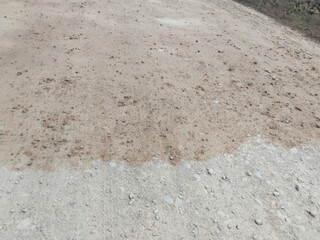 Initial stage of rural road construction with freshly laid concrete layer and water sprinkling for surface settling, part of multi-layer road building process in India