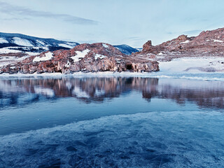 Baikal Lake in winter. Beautiful landscape with mountains reflected in ice of frozen Small Sea
