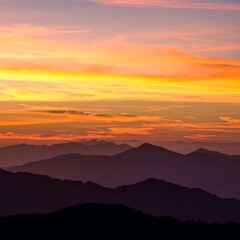 Majestic mountain range at sunset with vibrant orange and purple sky.
