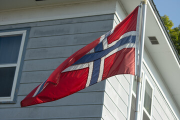 Norwegian flag in the sun by a blue building