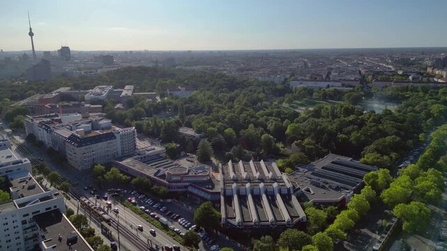 Sez and Volkspark Friedrichshain in Berlin, showcasing its lush greenery, a passing tram on a sunny day. Best aerial view flight fly reverse drone