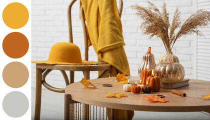 Burning candles in shape of pumpkins, autumn leaves and dry citruses on coffee table at home, closeup