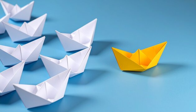 Yellow paper boat leading a fleet of white origami boats on a light blue background. Concept for business leadership, competitive advantage and market dominance