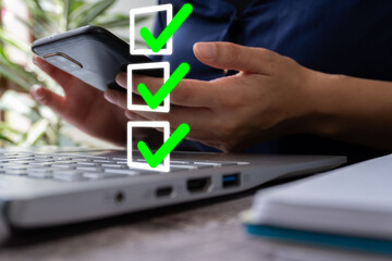 Person in front of a laptop with a smartphone with a checklist