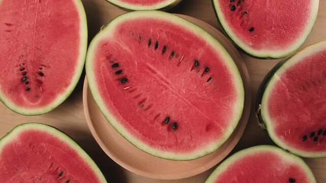 Close-up shot of half pieces of fresh red watermelons on a wooden dish, natural texture background pattern with tropical sweet and nutritious snack in hot summertime, healthy food with abundant fruit.