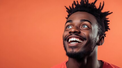 Close up of a happy african american man looking up with a bright smile against a solid orange colored background