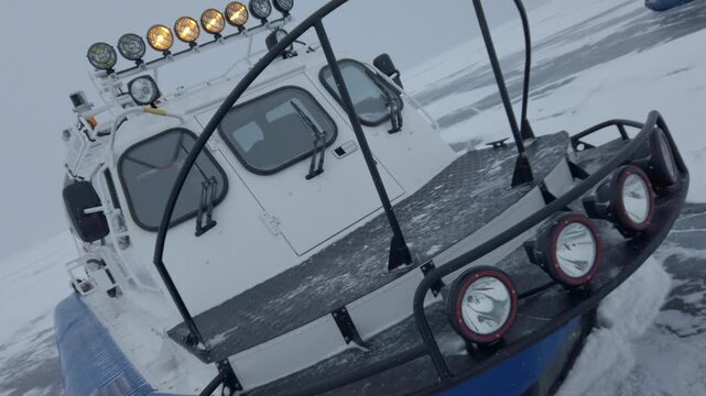 Extreme close-up of Hivus hovercraft nose stationed on cracked frozen winter lake. Unique air-cushion vehicle details, specialized transport in Arctic environment, technical helix shot. Expedition. 4k