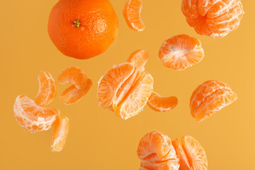 Flying sweet ripe mandarins on yellow background
