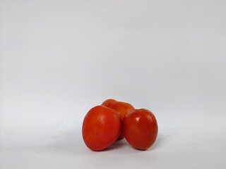 fresh red tomatoes placed on a white background, showcasing their natural texture and simple organic appearance.