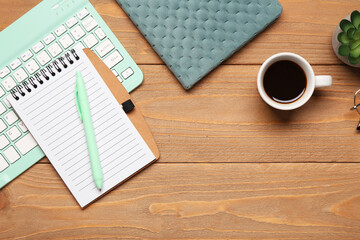 Composition with computer keyboard, cup of coffee and notebook on wooden background