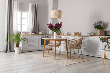 Vases with beautiful blooming lilac flowers in kitchen