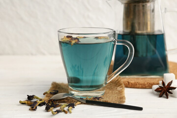 Cup with butterfly pea flower tea on white wooden background, closeup