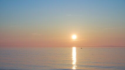 Beautiful sunrise over the calm sea with soft pastel colors in the sky and golden reflection on the water surface. A serene seascape perfect for relaxation and meditation concepts.