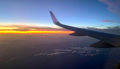 Obraz premium Airplane wing soars above cloudscape at sunset, vibrant orange and blue hues