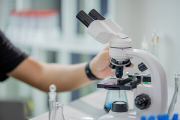 Scientist in laboratory conducting medical and biochemistry research, examining liquids in test tubes with advanced technology and microscope for healthcare, pharmaceutical development, and genetic in