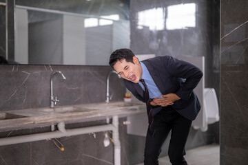 Young businessman suffering stomach ache in office restroom