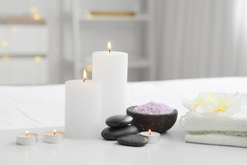 Spa composition with burning candles, sea salt and clean towels on light table