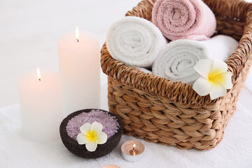 Obraz na płótnie Canvas Basket with clean towels, sea salt and burning candles on massage table