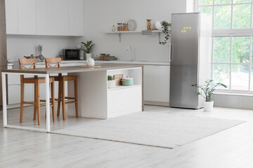 Interior of kitchen with modern fridge, counters and table