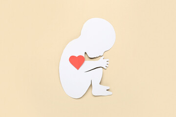 Paper baby figure with heart on beige background. IVF concept
