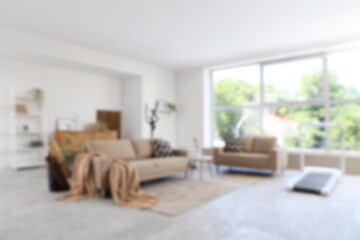 Blurred view of living room with sofas, elliptical machine and treadmill