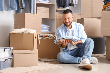 Young man packing clothes into wardrobe boxes in dressing room